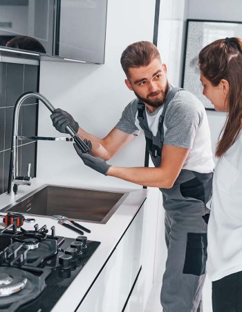 young-professional-plumber-in-grey-uniform-shows-r-resize.jpg